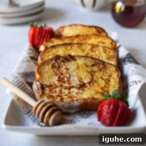 Repurposed Buttermilk French Toast 13 Buttermilk French toast layered on a white plate with strawberries and a sprinkle of powdered sugar.