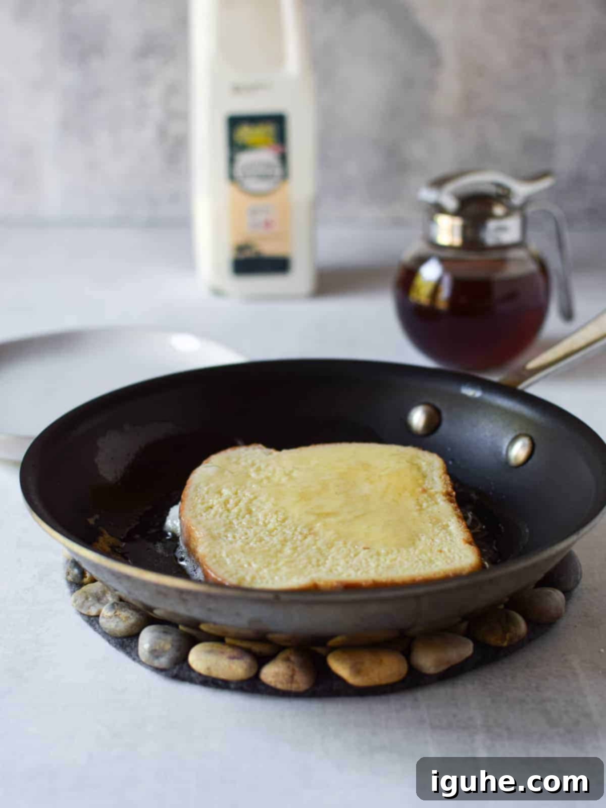 Repurposed Buttermilk French Toast 9 A soaked slice of bread placed in a frying pan with sizzling butter, starting to cook.