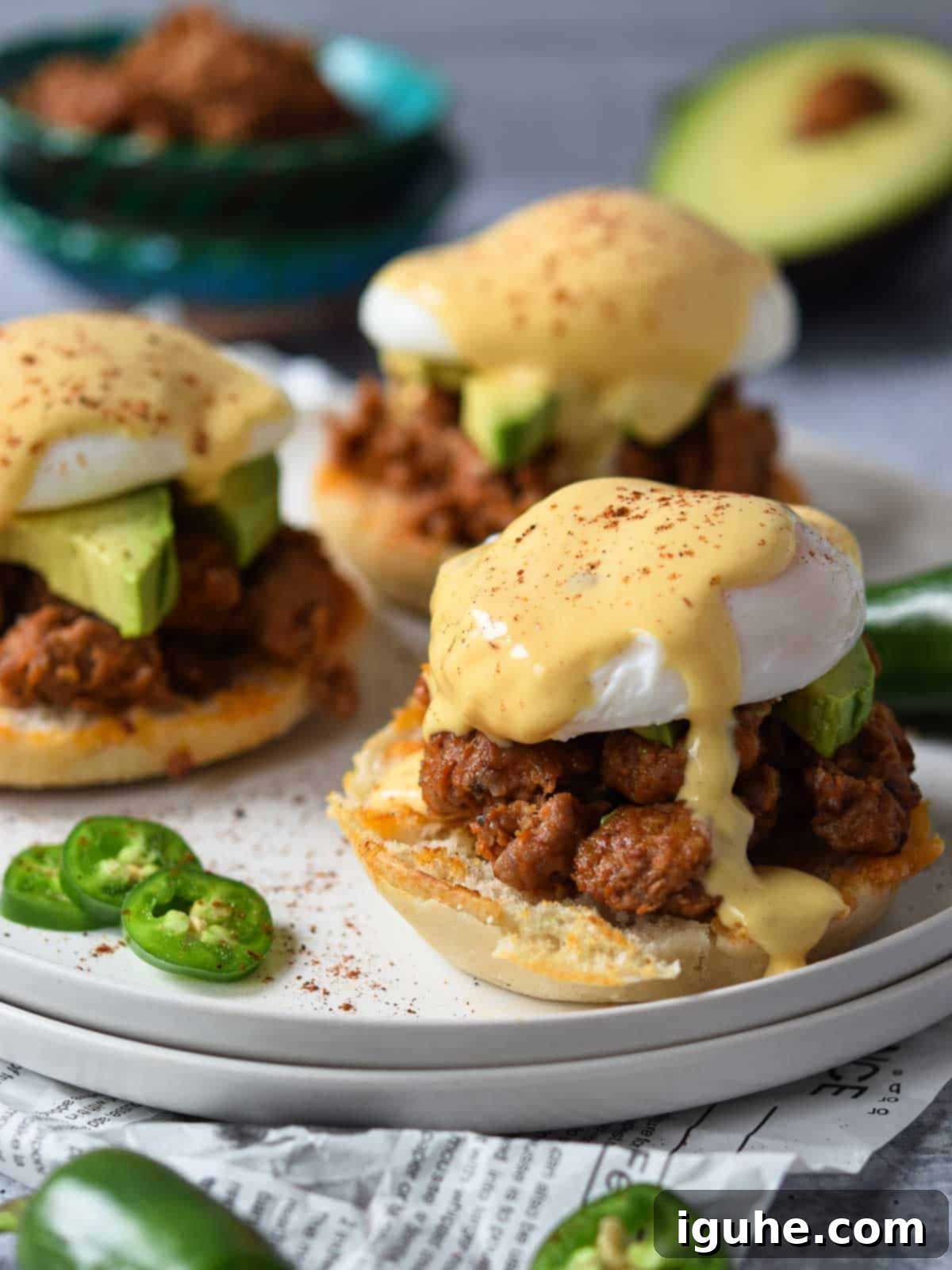 Three Mexican Eggs Benedict on a white plate with rich, dripping hollandaise sauce and fresh cilantro garnish.