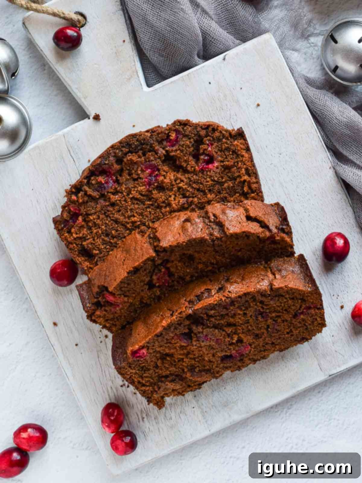Overhead of 3 slices of cranberry gingerbread loaf on grey board.