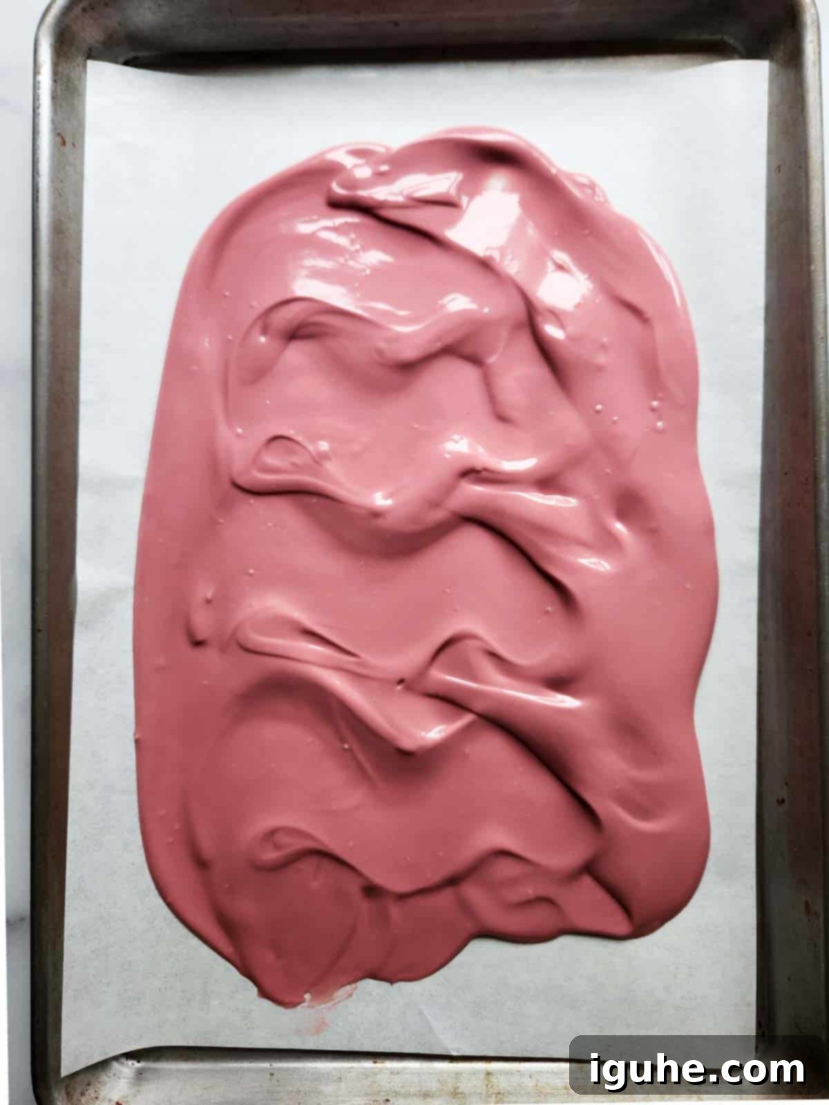 Blush Ruby Chocolate Bark 6 Melted pink chocolate spread out on parchment paper.
