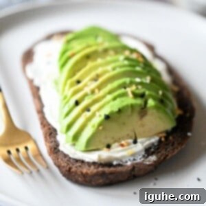Gourmet Cream Cheese Avocado Toast 9 Close-up of sliced avocado on pumpernickel bread with cream cheese and spices.