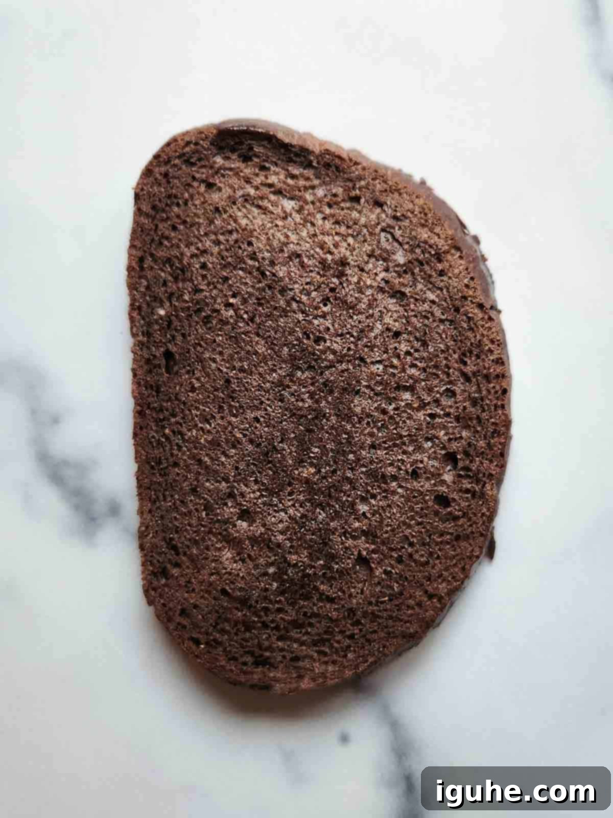 Gourmet Cream Cheese Avocado Toast 4 One slice of pumpernickel bread on a white marble surface, ready to be toasted.