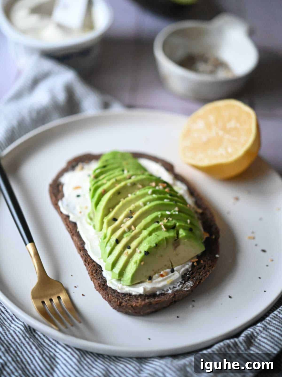 Gourmet Cream Cheese Avocado Toast 8 Close-up view of a beautifully prepared cream cheese avocado toast on pumpernickel bread, garnished with a light sprinkle of everything bagel seasoning.