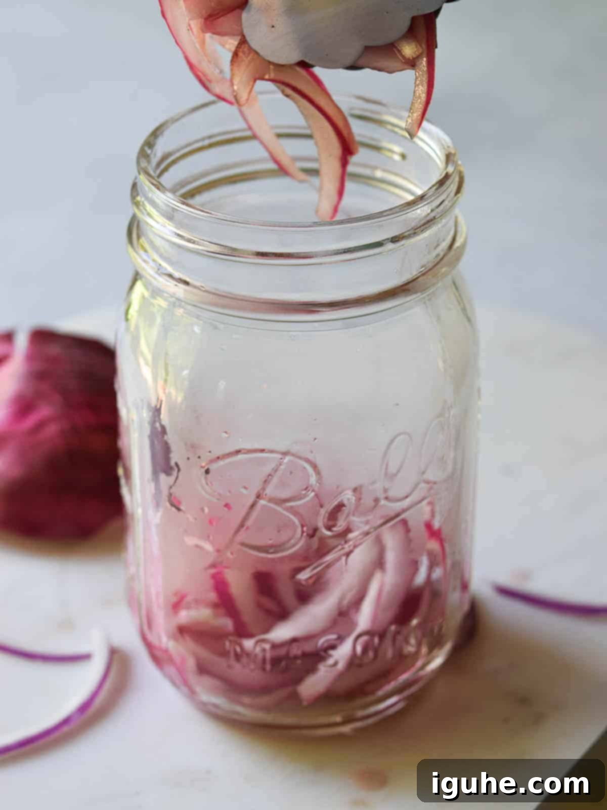Sweet Heat Pickled Onions 7 Pickled red onions being transferred into a mason jar for storage.