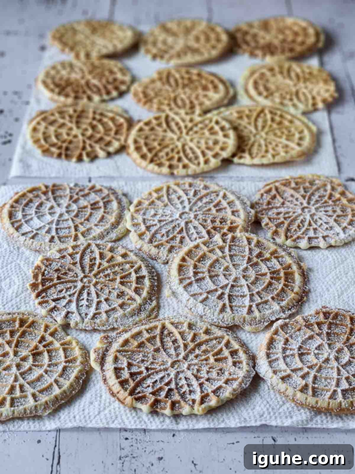 Effortless Lemon Pizzelle 11 Cooked lemon pizzelles on paper towels with powdered sugar on them.
