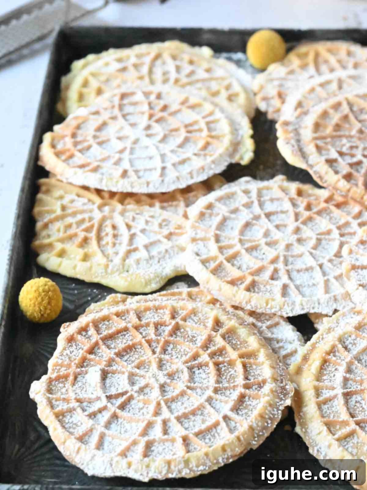 Effortless Lemon Pizzelle 12 Close-up of lemon pizzelles stacked with fresh lemons in the background.