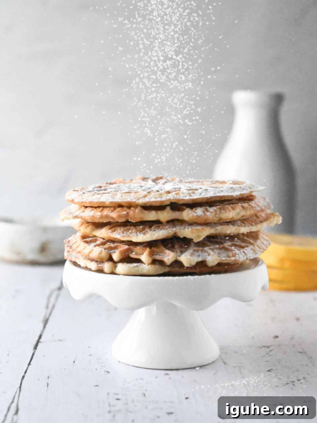 Effortless Lemon Pizzelle 13 Two lemon pizzelles on a white plate with fresh lemon slices and mint.