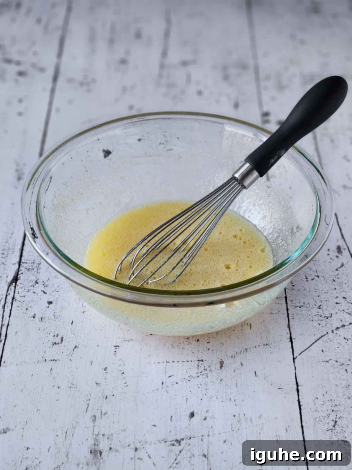Effortless Lemon Pizzelle 5 Sugar and eggs mixed together in a clear bowl with a whisk.