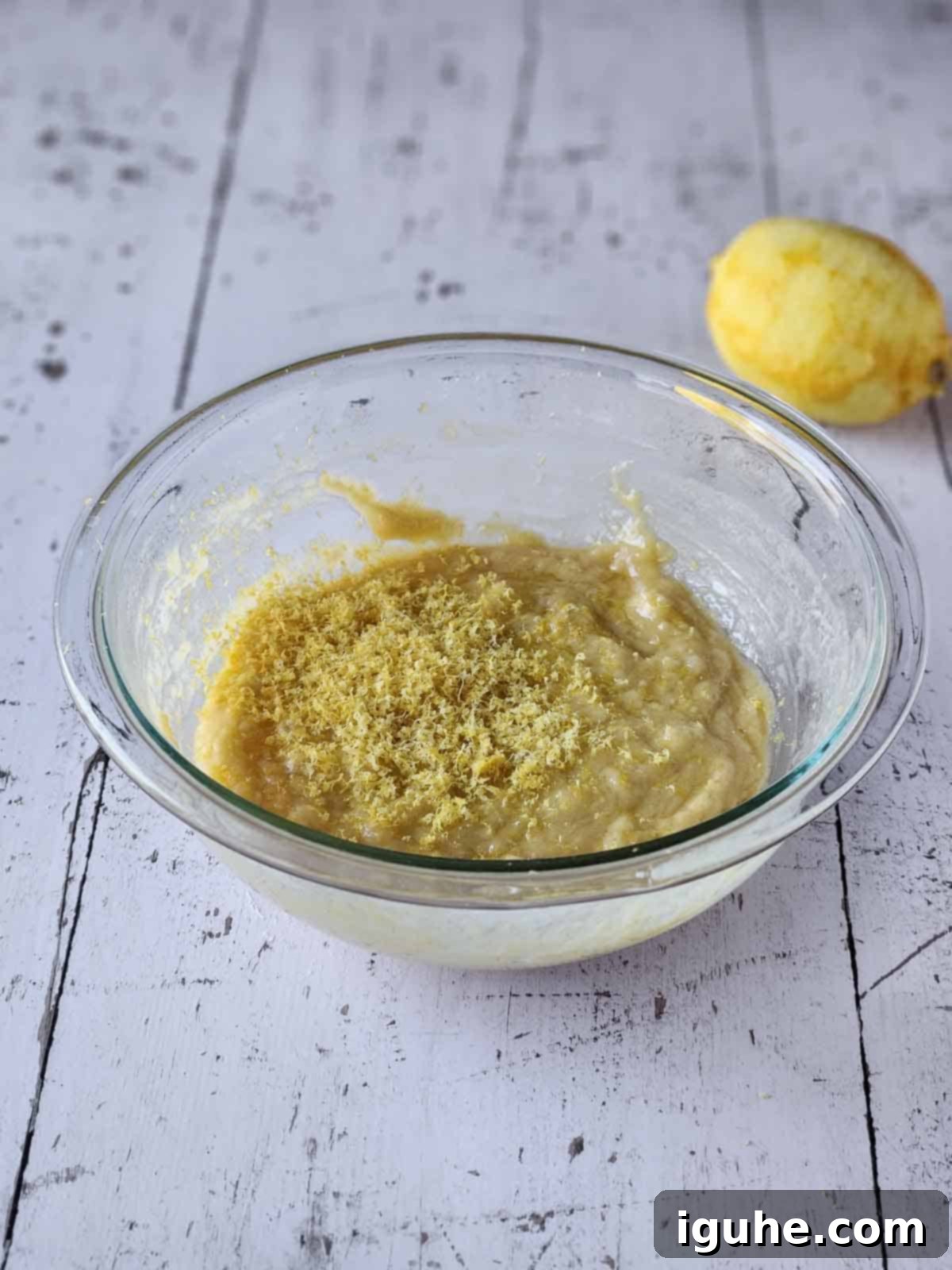 Effortless Lemon Pizzelle 8 Batter for lemon pizzelles with lemon zest on top in a clear bowl.