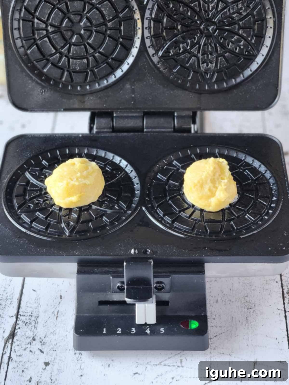 Effortless Lemon Pizzelle 9 Batter being dropped onto a pizzelle maker for lemon pizzelles.