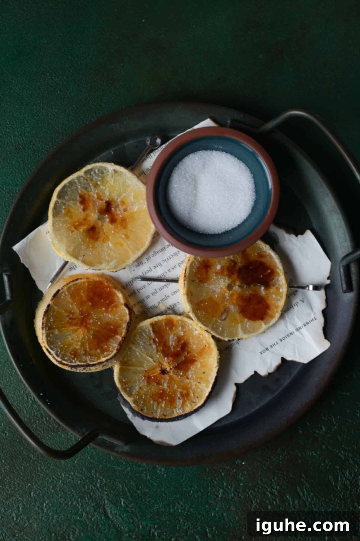 Caramelized Lemonade Mimosa 3 Lemon brûlée slices on a black tray with sugar.