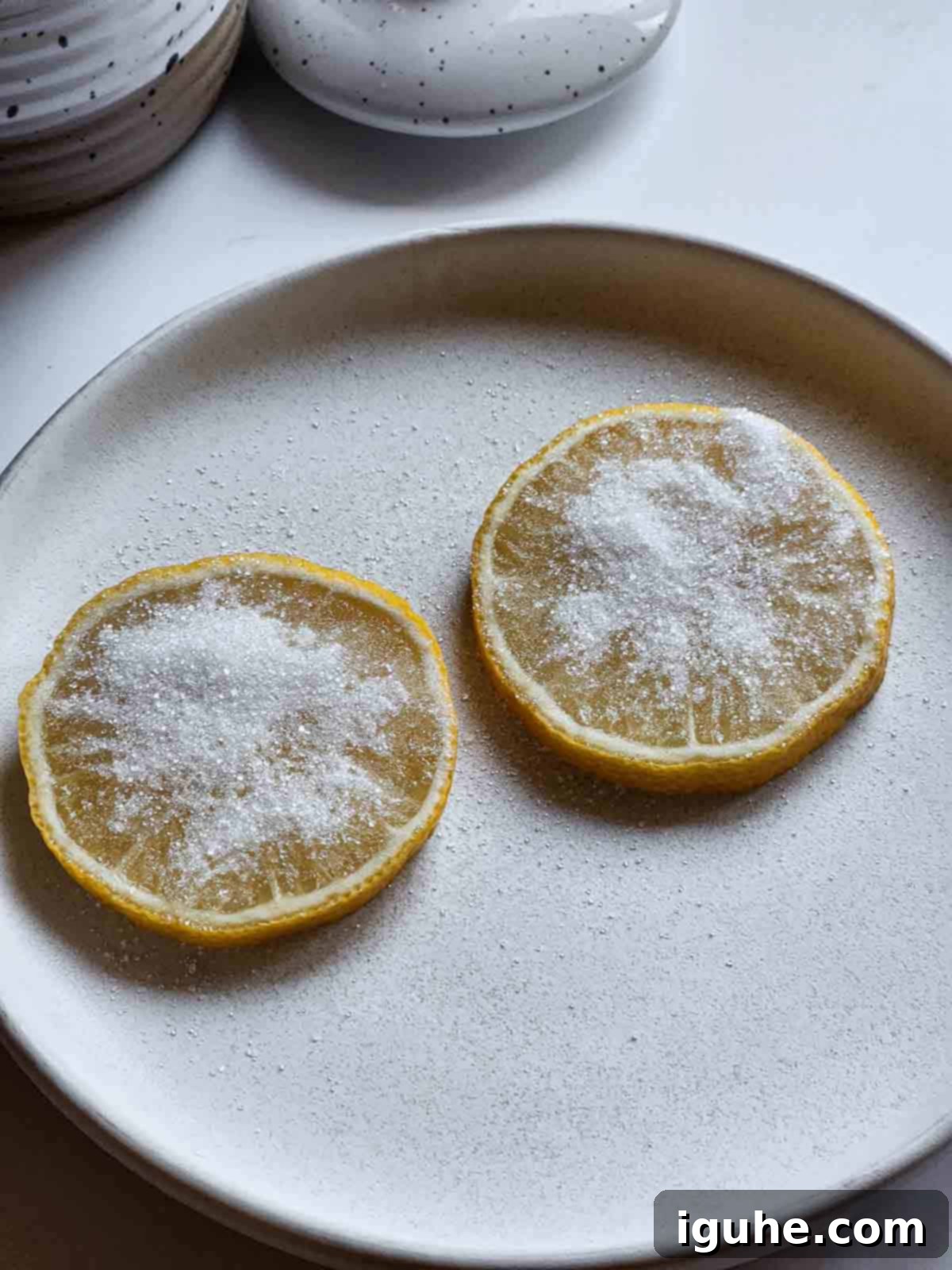 Caramelized Lemonade Mimosa 4 Two lemon slices with sugar on them on a white plate.