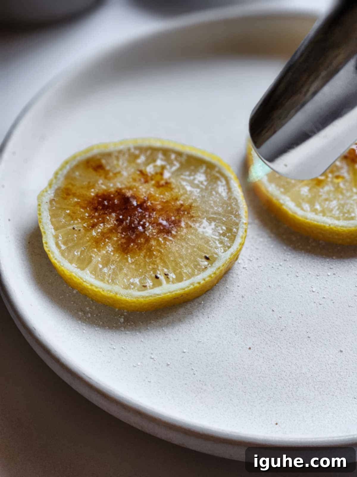 Caramelized Lemonade Mimosa 5 Sugared lemon slices with a kitchen torch pointed at them getting torched.