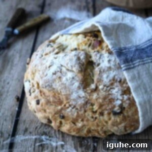 Sun-Kissed Apricot and Currant Irish Soda Bread 10 Irish soda bread wrapped in a beige and blue towel on a wood surface.