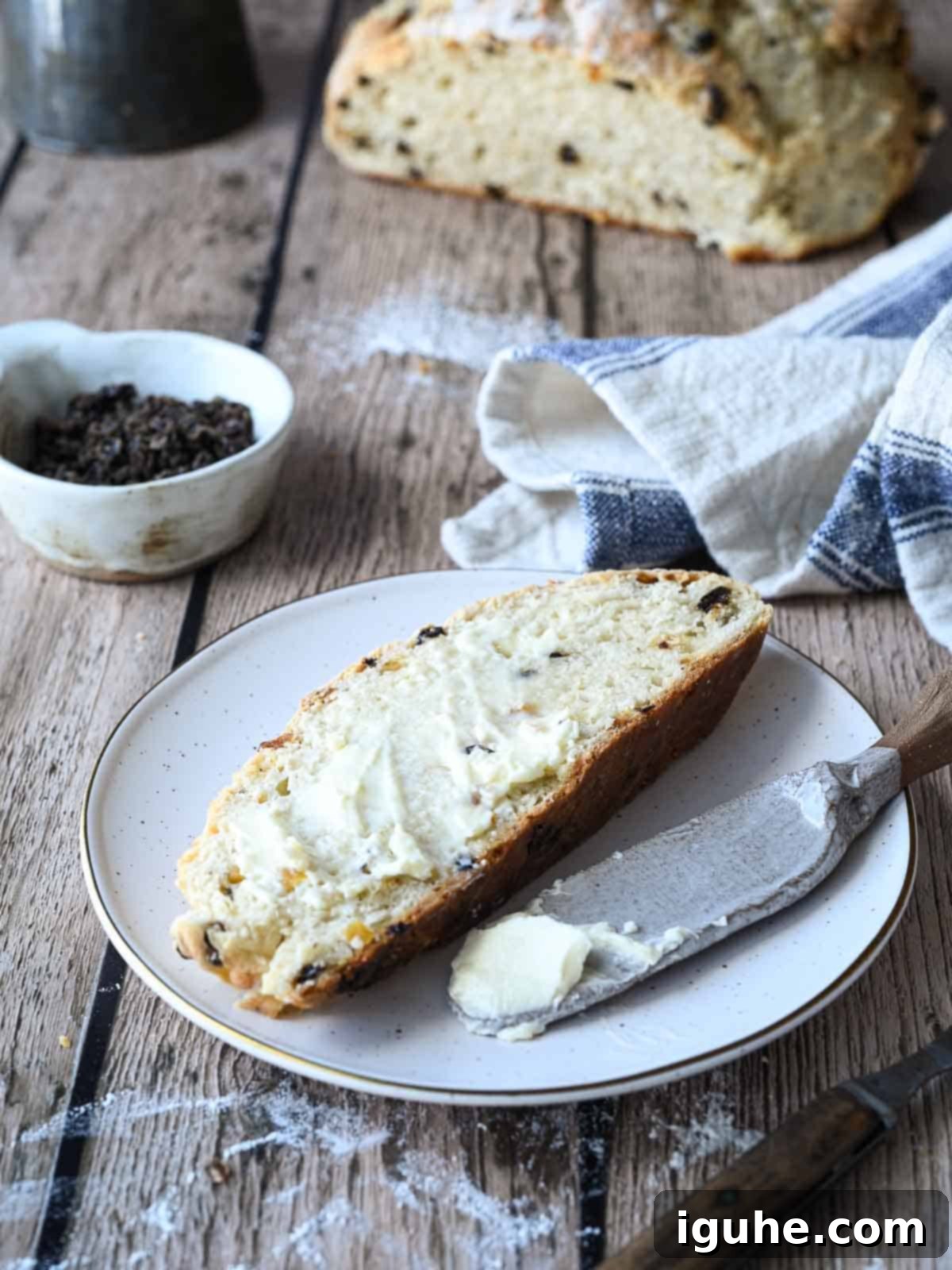 Sun-Kissed Apricot and Currant Irish Soda Bread 9 A slice of Irish soda bread with currants and apricots in the background.