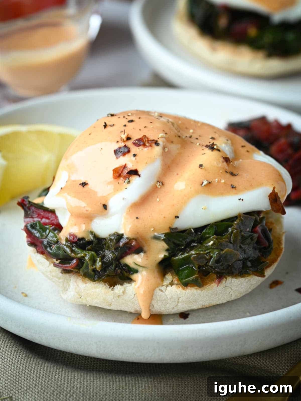 Swiss chard eggs Florentine on a white plate with a lemon in the background, showcasing the vibrant colors of the dish.
