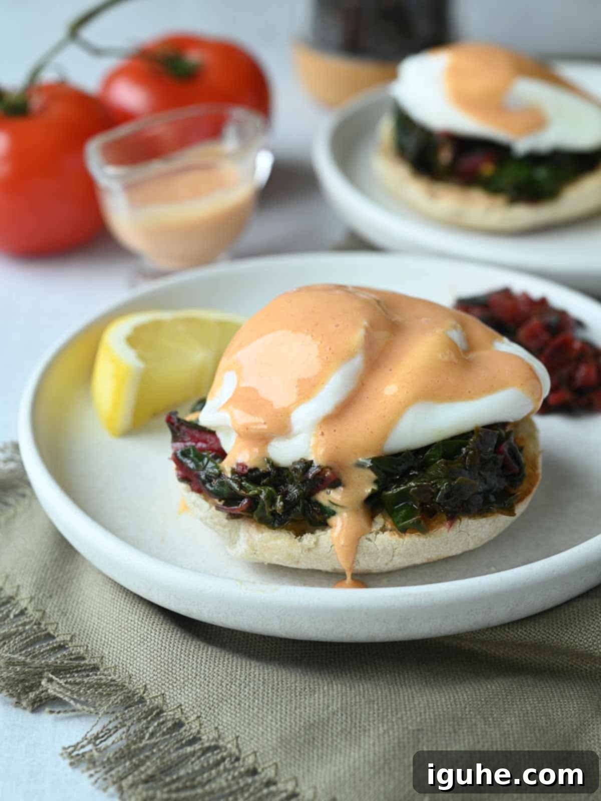 Swiss Chard Eggs Florentine with Zesty Tomato Hollandaise 8 Eggs Florentine topped with a generous drizzle of tomato hollandaise sauce, which gently drips onto the white plate.