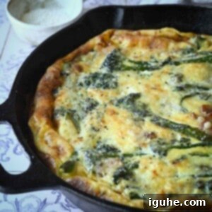 Ultimate Broccolini Bacon Parmesan Frittata 8 Close-up of broccolini frittata in a skillet with parmesan cheese in the background.