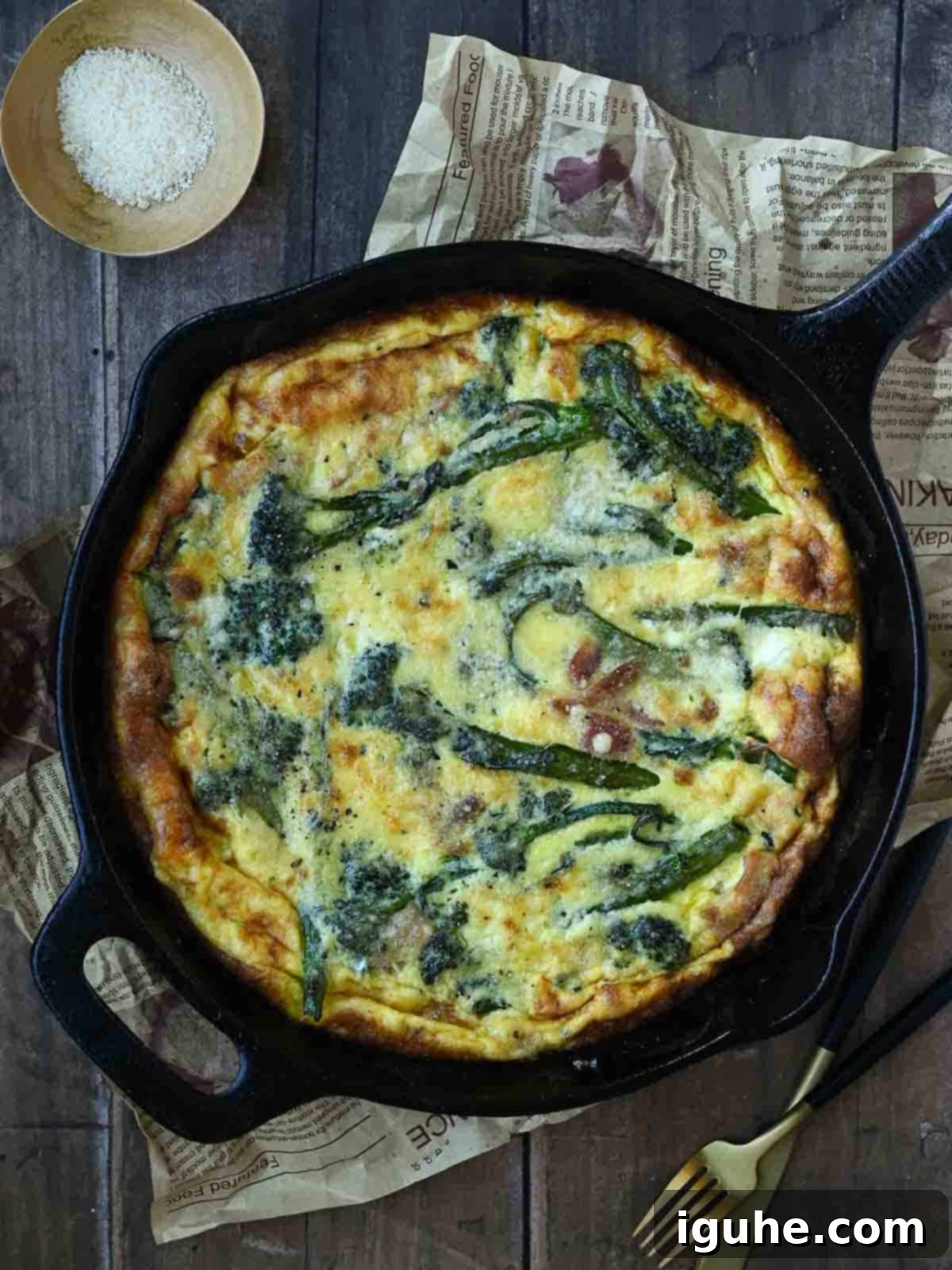 Ultimate Broccolini Bacon Parmesan Frittata 6 Overhead view of broccolini frittata in a black skillet on a wooden surface.