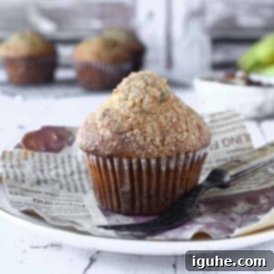 Irresistible Banana Pecan Muffins 12 Close-up of a banana muffin on a white plate with muffins in the background.