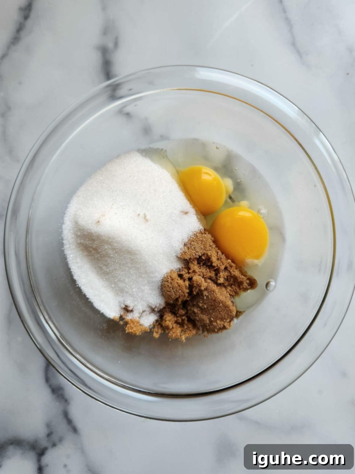 Irresistible Banana Pecan Muffins 5 Eggs and sugar in a clear bowl.