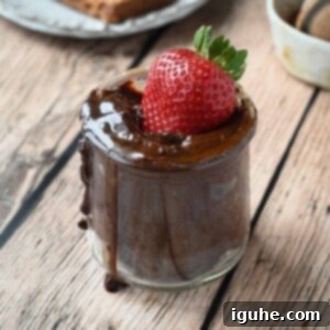 Close-up of a strawberry dipped inside a jar of chocolate tahini spread.