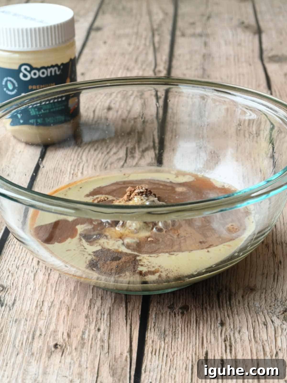 Ingredients in a clear mixing bowl for tahini chocolate.