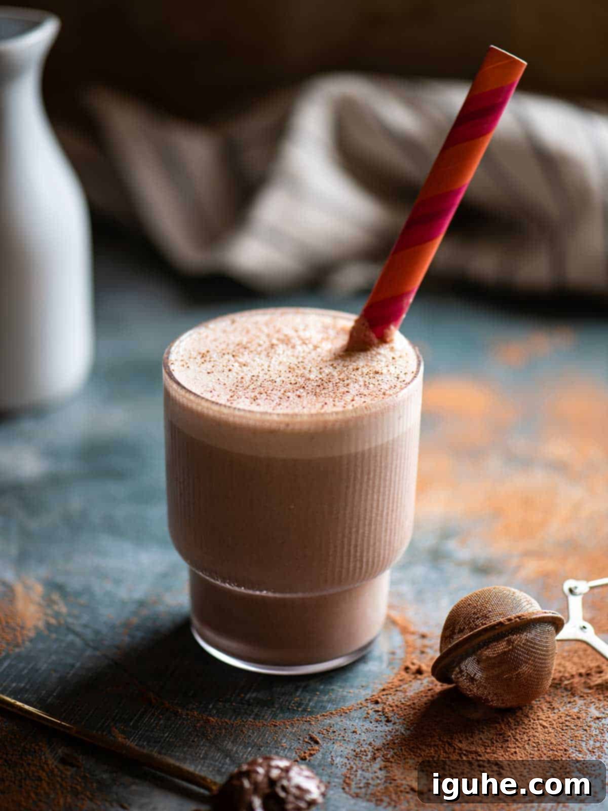 Creamy Chocolate Tahini Oat Milk Smoothie in a ribbed glass with an orange striped straw, perfect for a healthy breakfast.