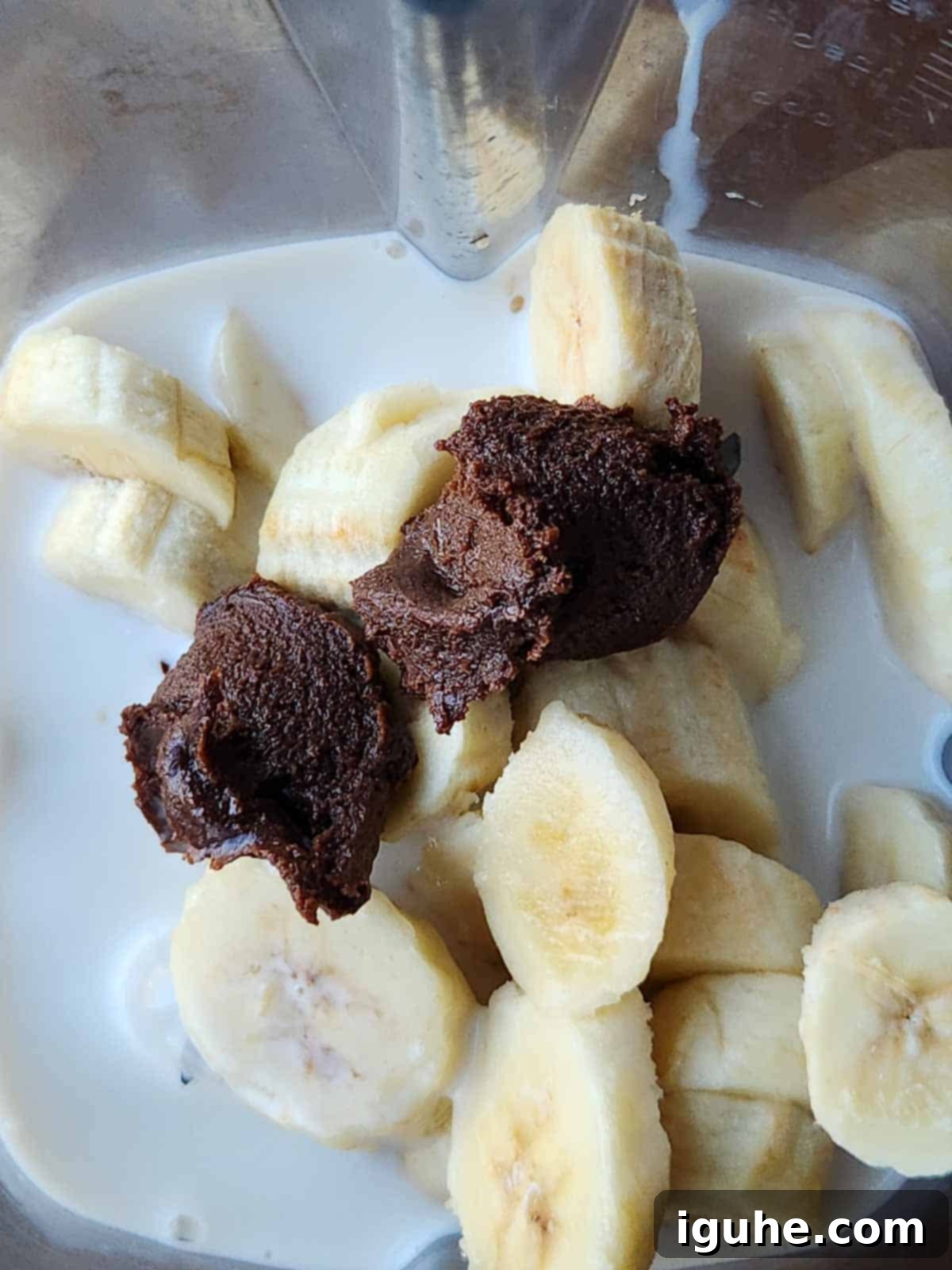 Decadent Chocolate Tahini Oat Milk Smoothie 4 All smoothie ingredients: frozen banana slices, oat milk, and chocolate tahini being added to a blender.