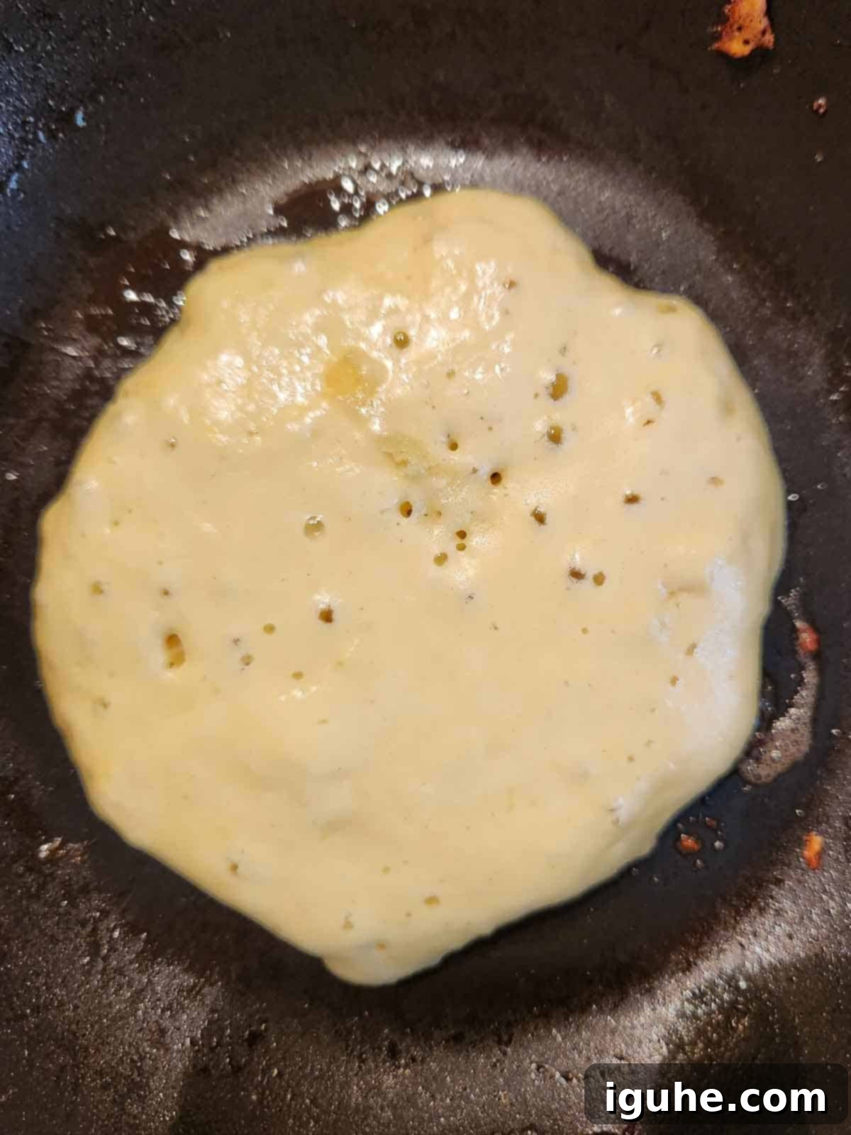 Cinnamon Swirl Sweet Cream Pancakes 6 Sweet cream pancake batter cooking in a non-stick skillet, with small bubbles starting to form on the surface.