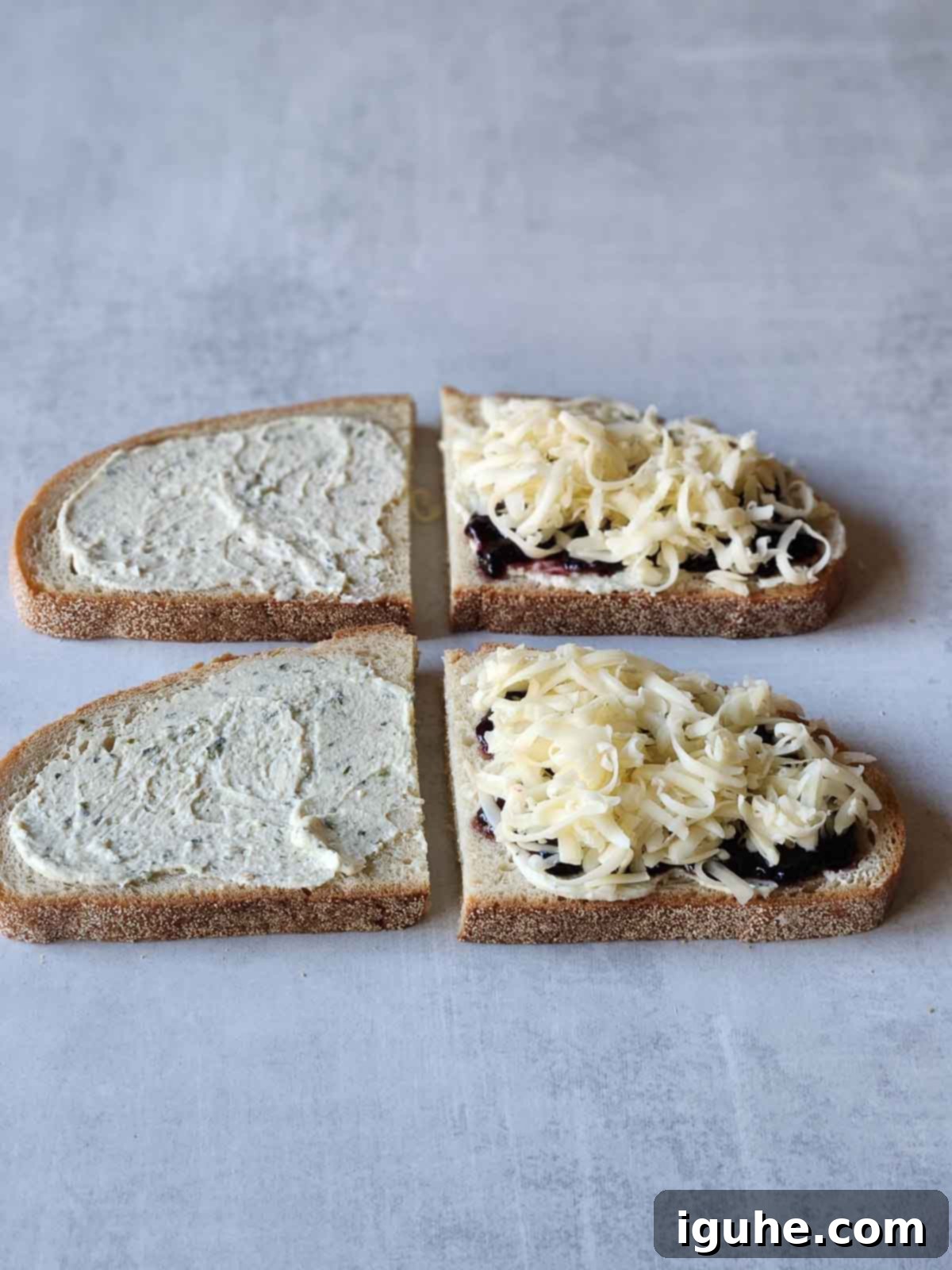 Blackberry Boursin Grilled Delight 5 Two slices of bread with blackberry jam spread on top, followed by shredded Fontina cheese.