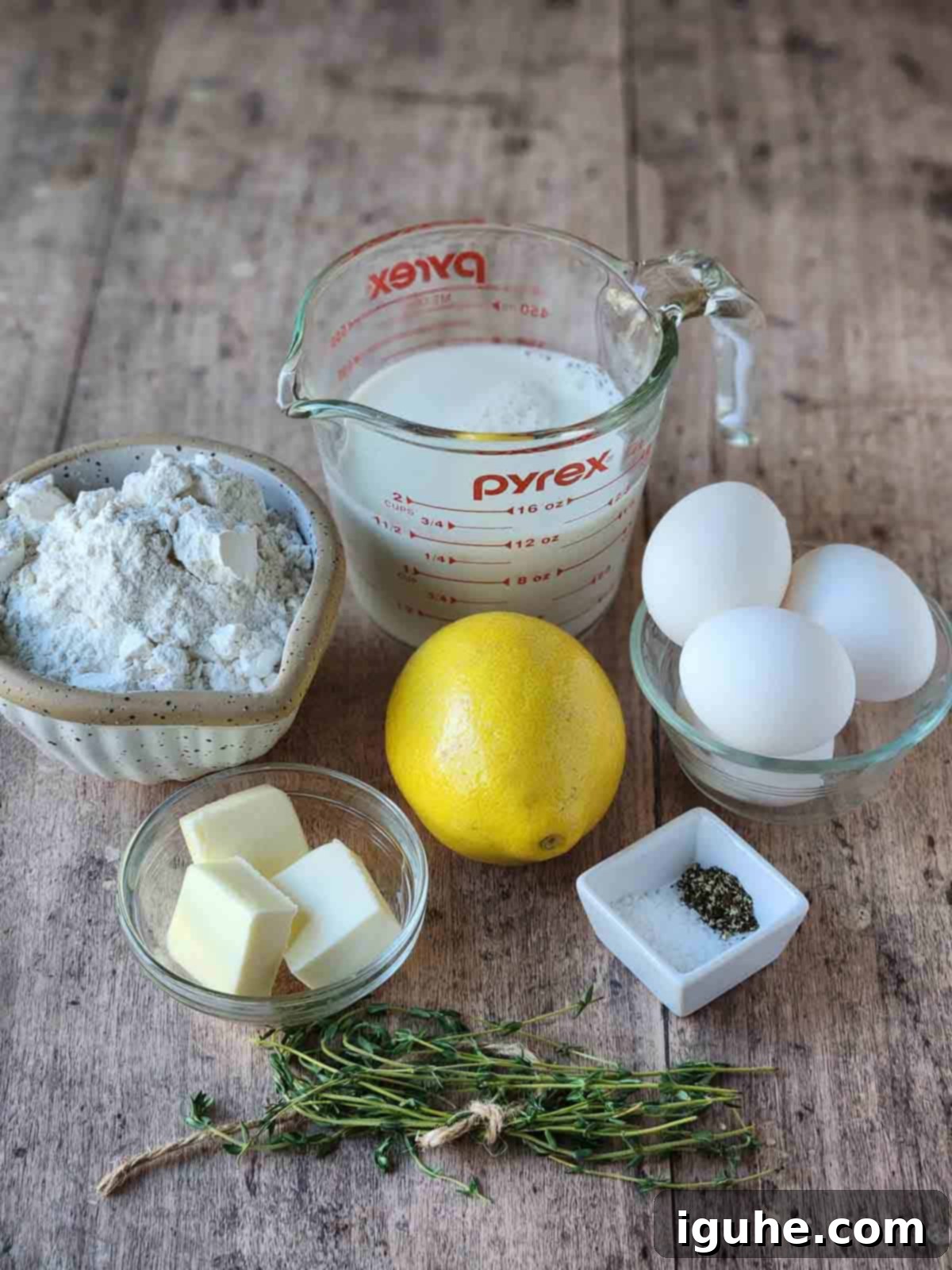 Fluffy Lemon Thyme Delights 3 Ingredients for lemon-thyme popovers arranged artfully on a warm wood surface, ready for baking.