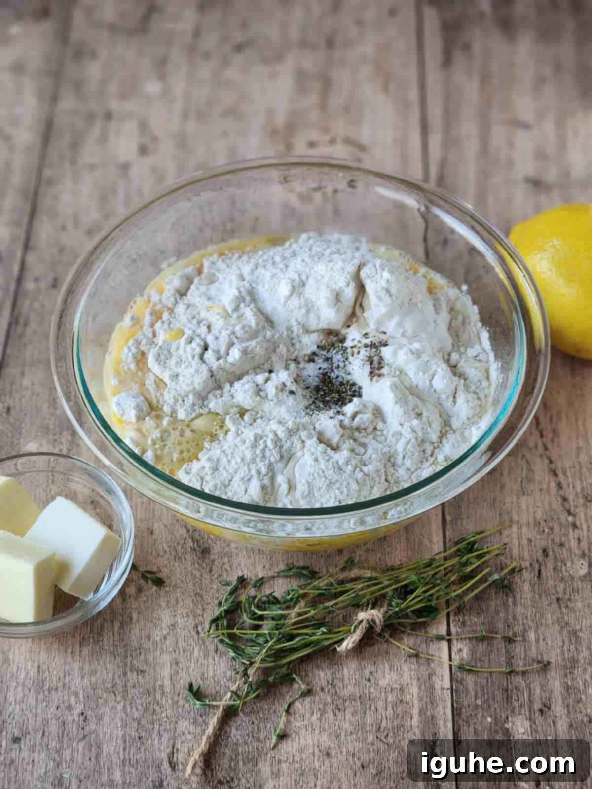 Fluffy Lemon Thyme Delights 5 The same popover batter in a clear bowl, now with the addition of fresh thyme leaves and bright lemon zest on the side.