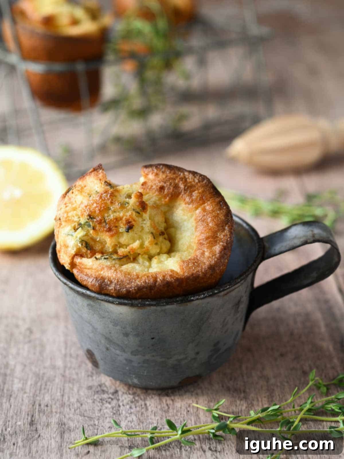 Fluffy Lemon Thyme Delights 9 One golden lemon and thyme popover nestled in a vintage metal cup, with fresh thyme and lemons softly blurred in the background.