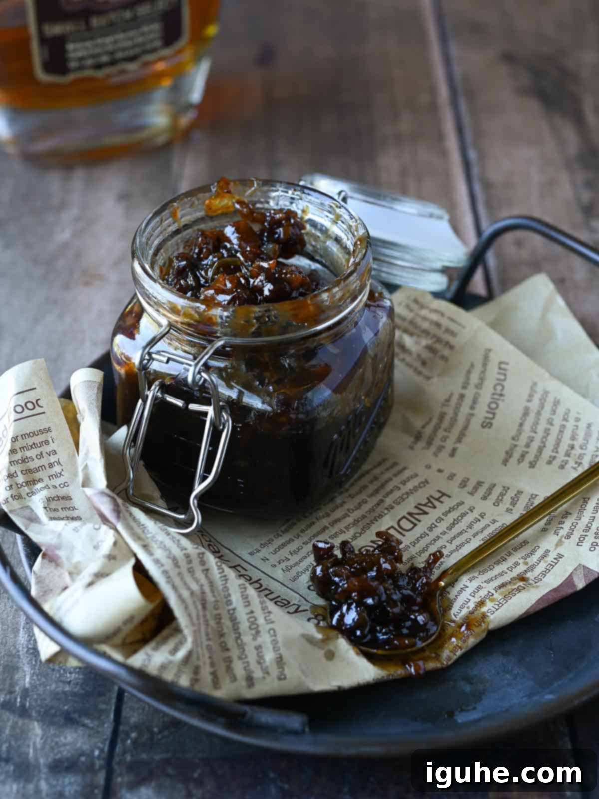 Bourbon and bacon jam in a clear jar with some on a spoon.