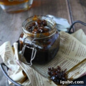 Bourbon-Kissed Bacon Bliss 10 Bourbon and bacon jam in a clear glass jar on a tray lined with brown parchment paper.