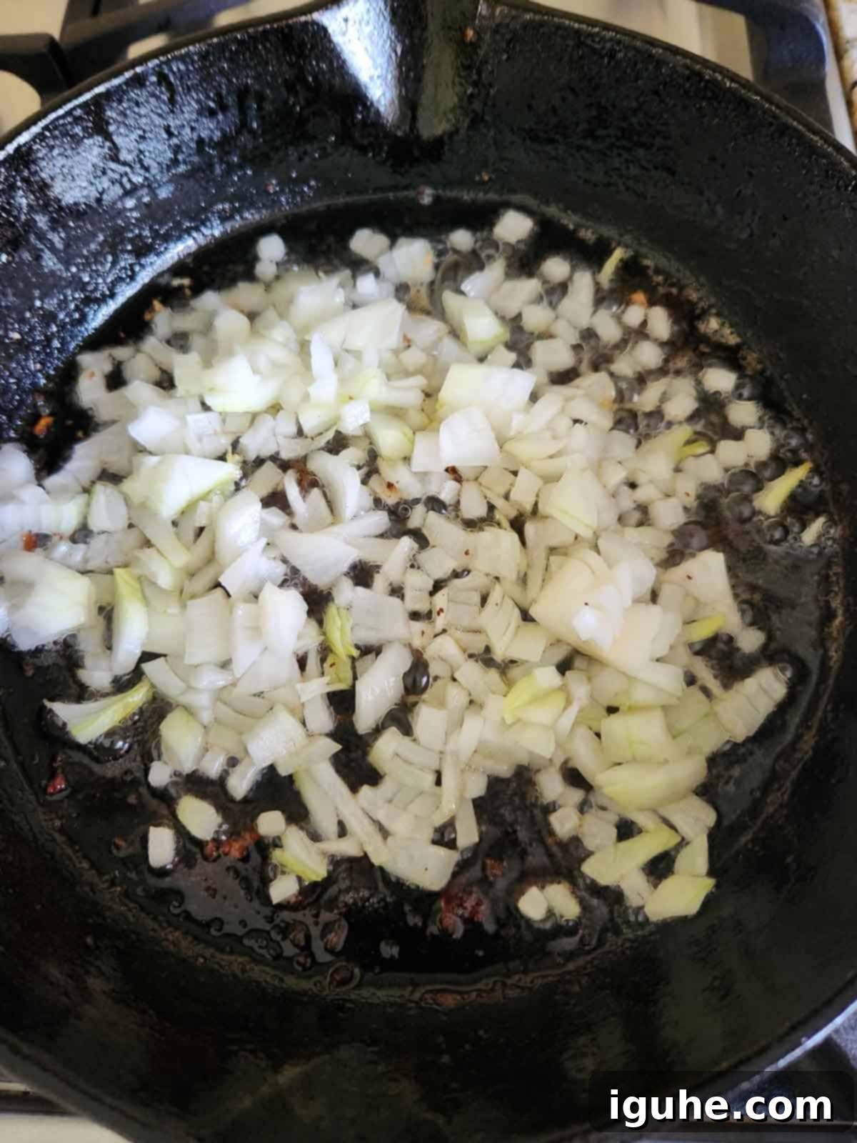 Bourbon-Kissed Bacon Bliss 4 Sautéed onions in a black cast iron skillet.
