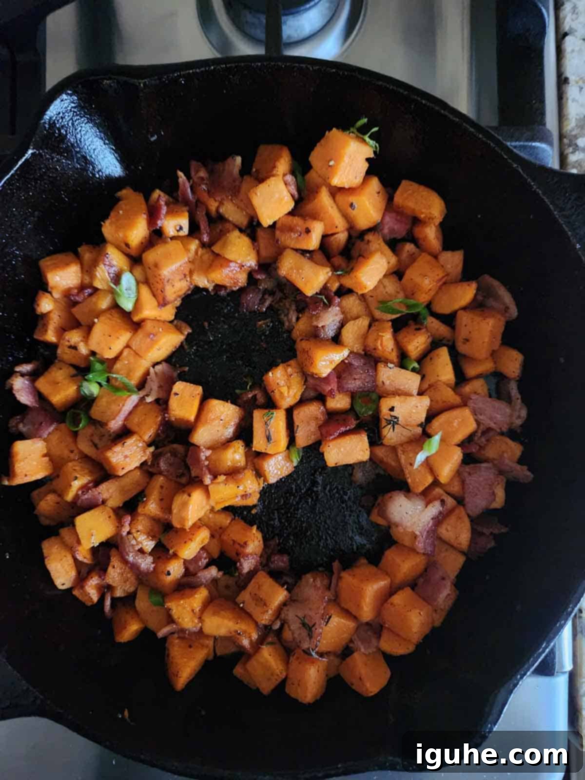 Sunrise Sweet Potato Bacon Medley 8 Sweet potato hash in a skillet with 2 wells in the middle for eggs.