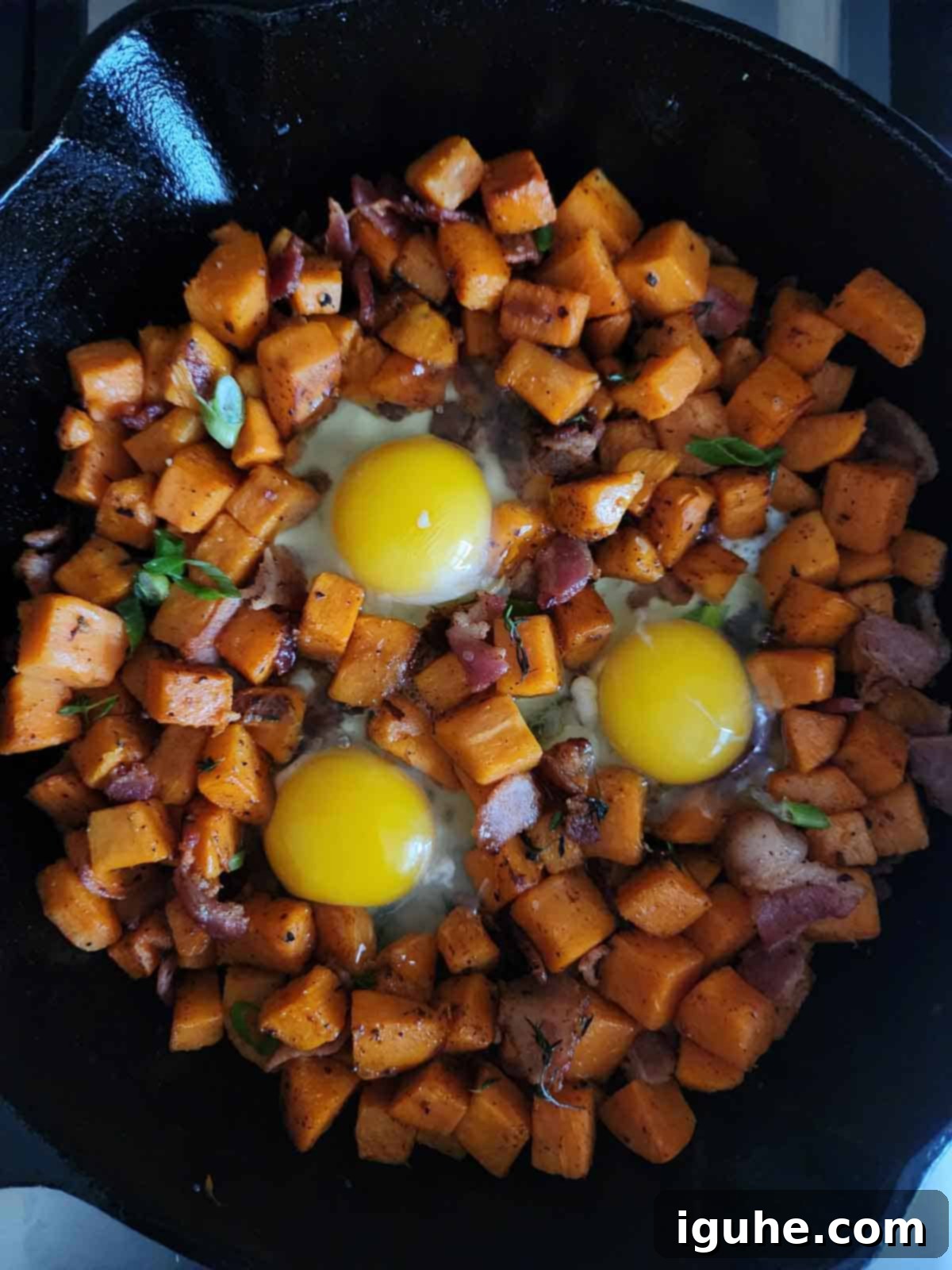 Sunrise Sweet Potato Bacon Medley 9 Hash in a skillet with 3 eggs in the center.
