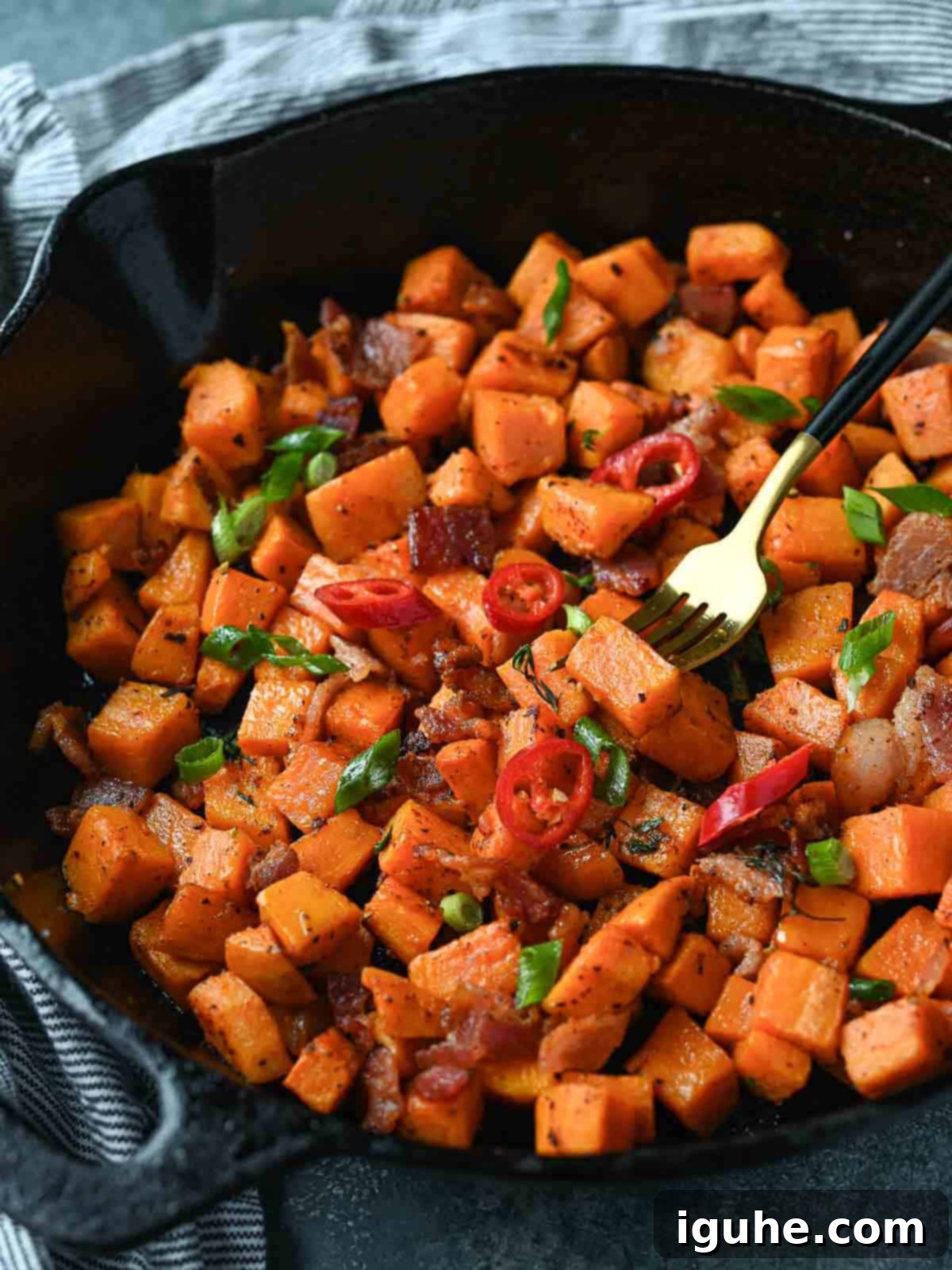 Sunrise Sweet Potato Bacon Medley 10 Sweet potato hash in a cast iron skillet with a fork in it.