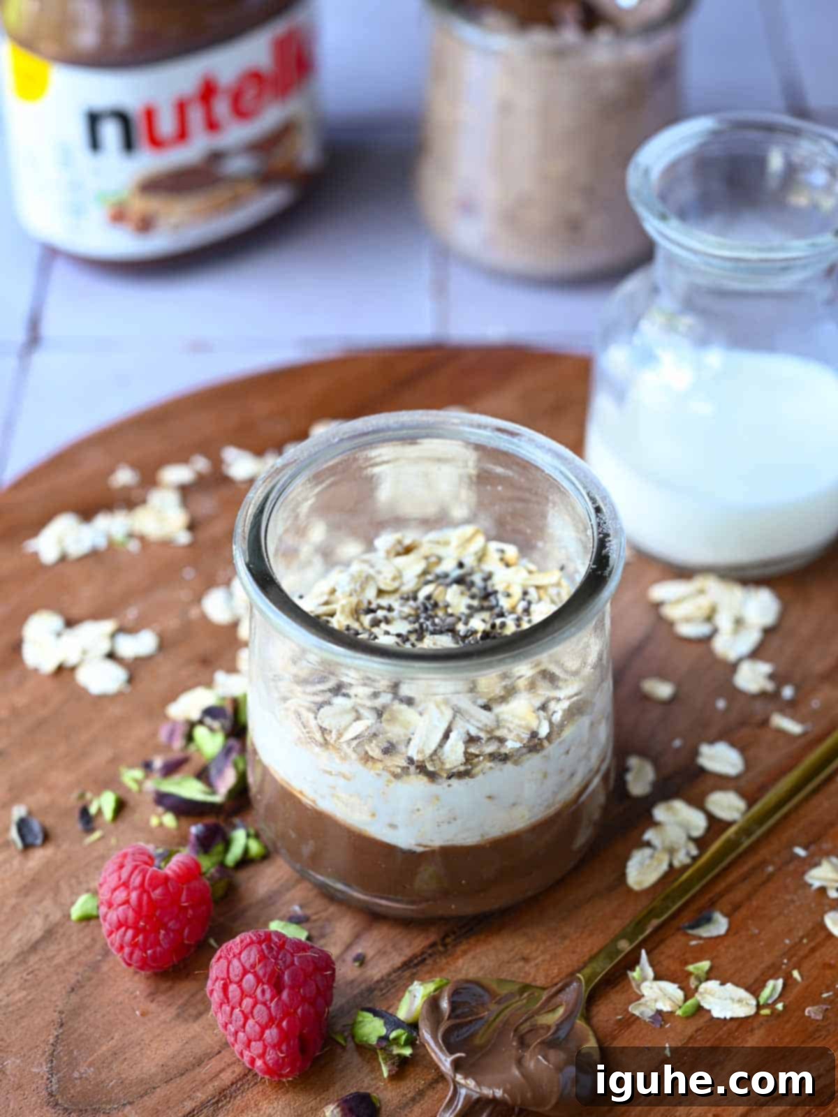 Decadent Nutella Overnight Oats 5 Nutella overnight oats layered in a glass jar with milk in the background.