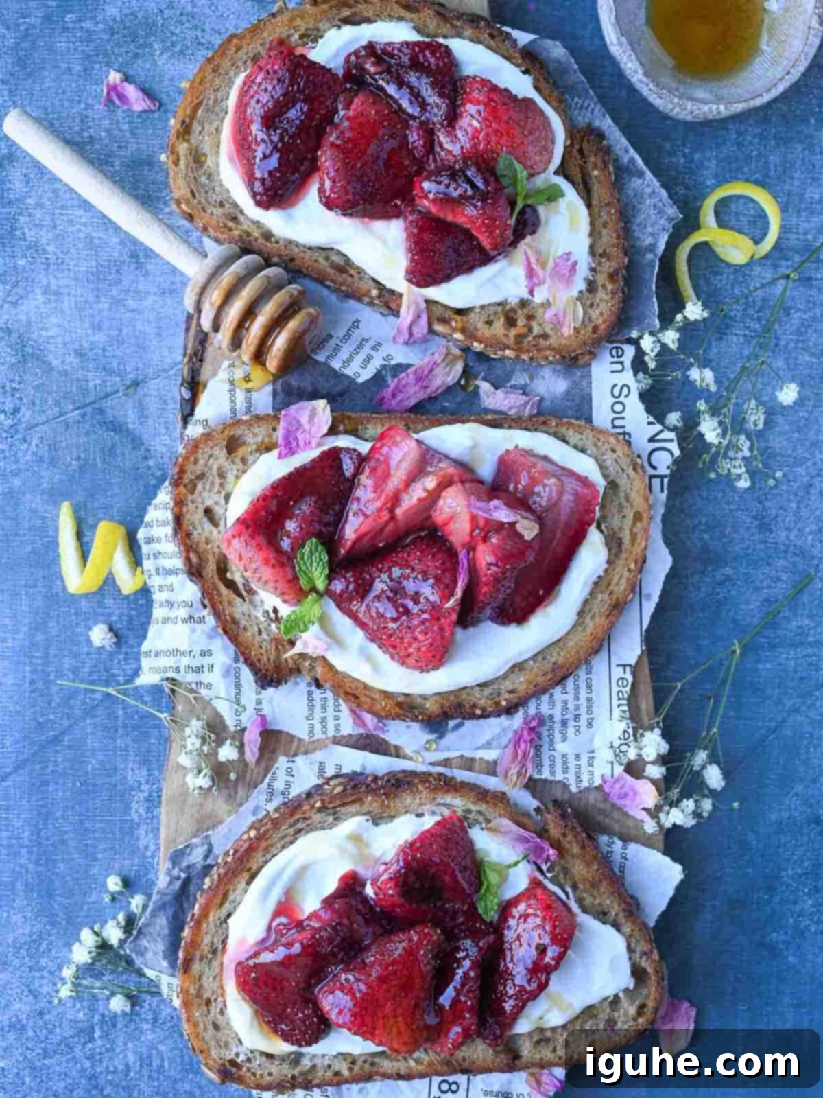 Roasted Strawberry Labneh Toast 3 Overhead of three labneh toasts with strawberries on a blue surface, ready to be served.