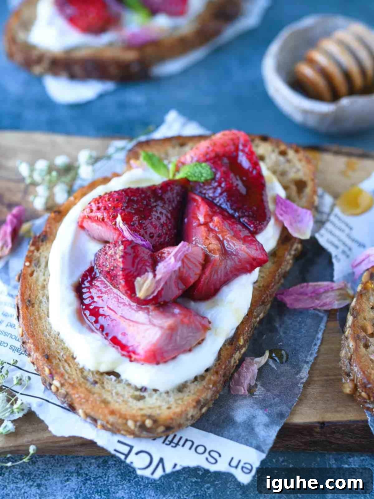 Roasted Strawberry Labneh Toast 6 Roasted strawberries and labneh on toast over a cutting board, garnished with mint.