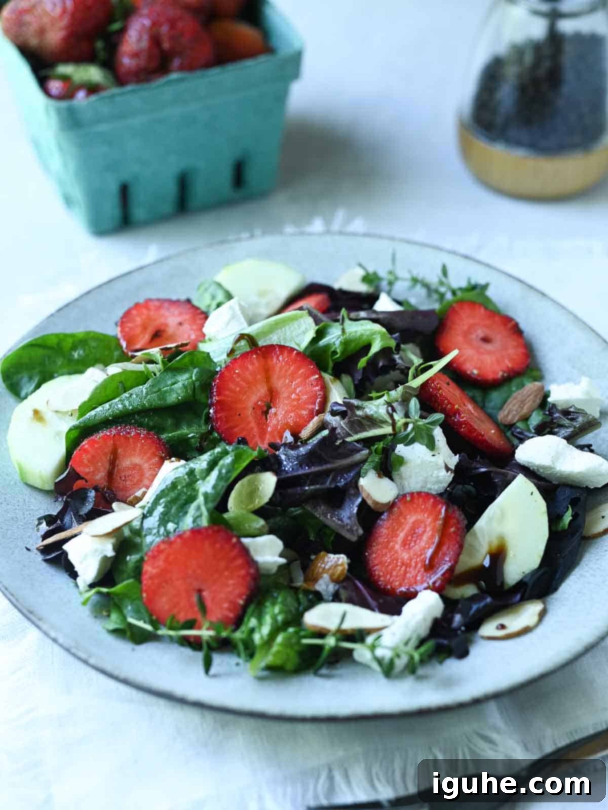 Salad with lettuce and strawberries on a grey plate.