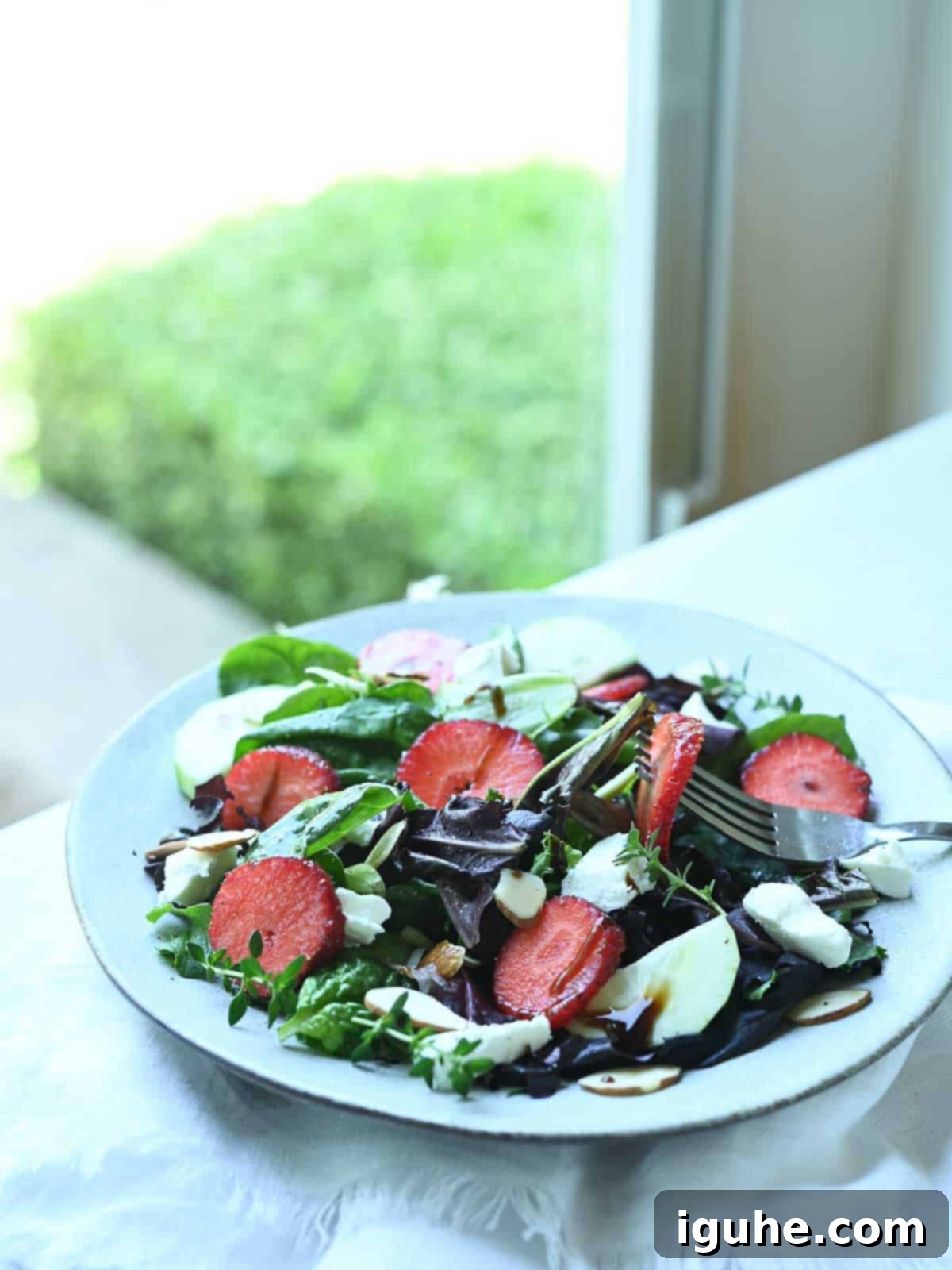 Strawberry Goat Cheese Salad 4 A serving of strawberry salad on a plate next to an open window.
