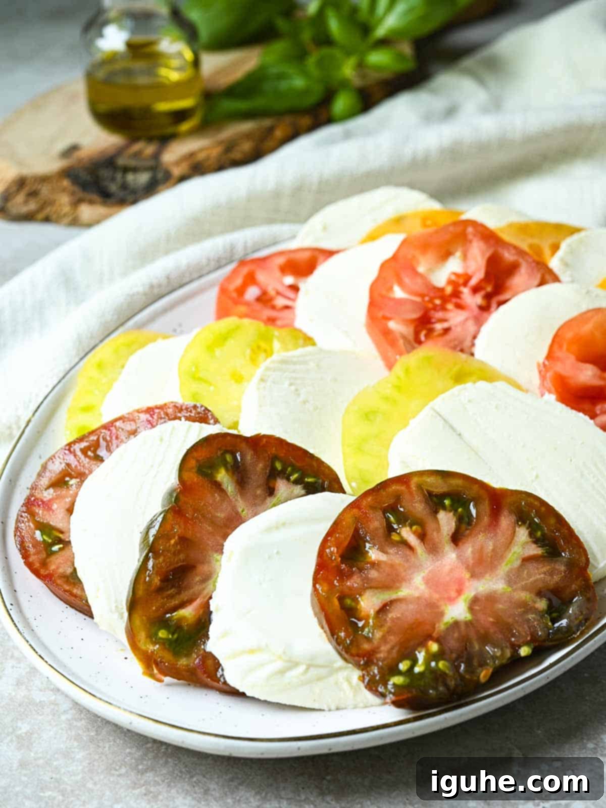 Vibrant Heirloom Caprese Salad 5 Sliced heirloom tomatoes and mozzarella on a white platter.