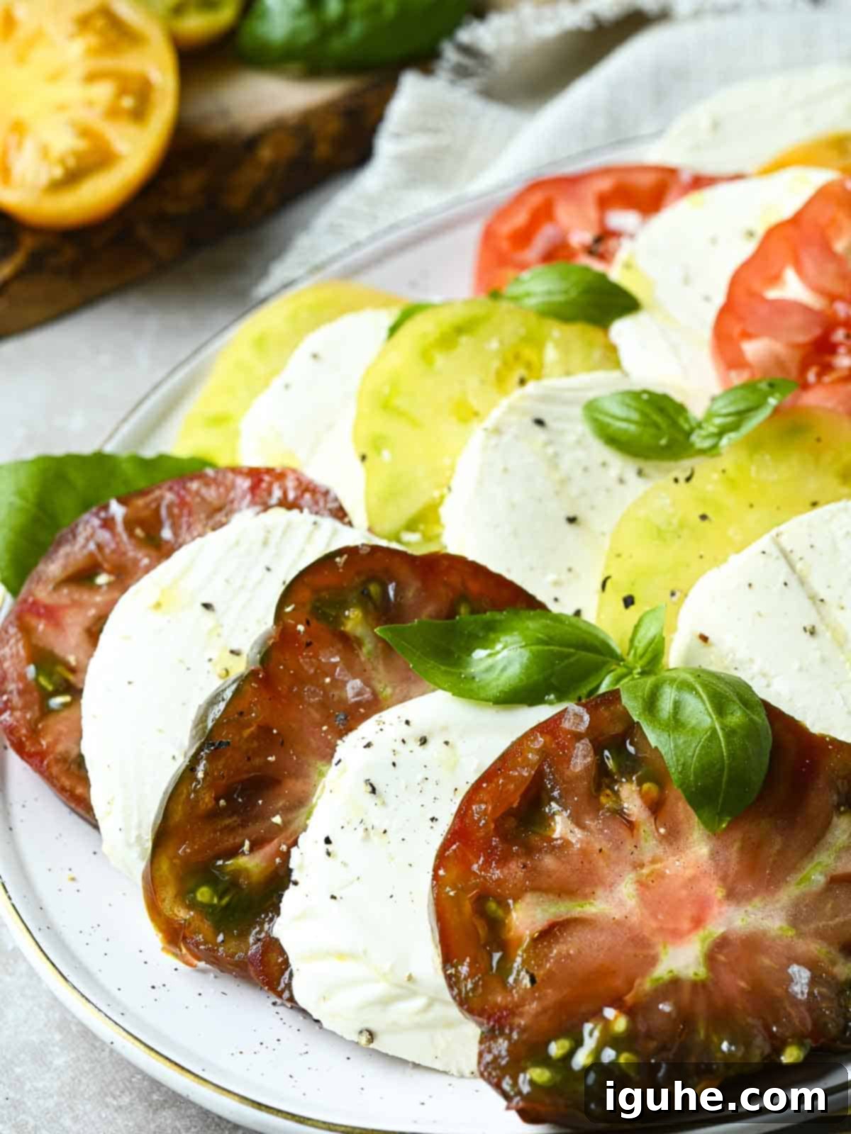 Vibrant Heirloom Caprese Salad 7 Italian heirloom tomato Caprese salad on a white plate with basil.