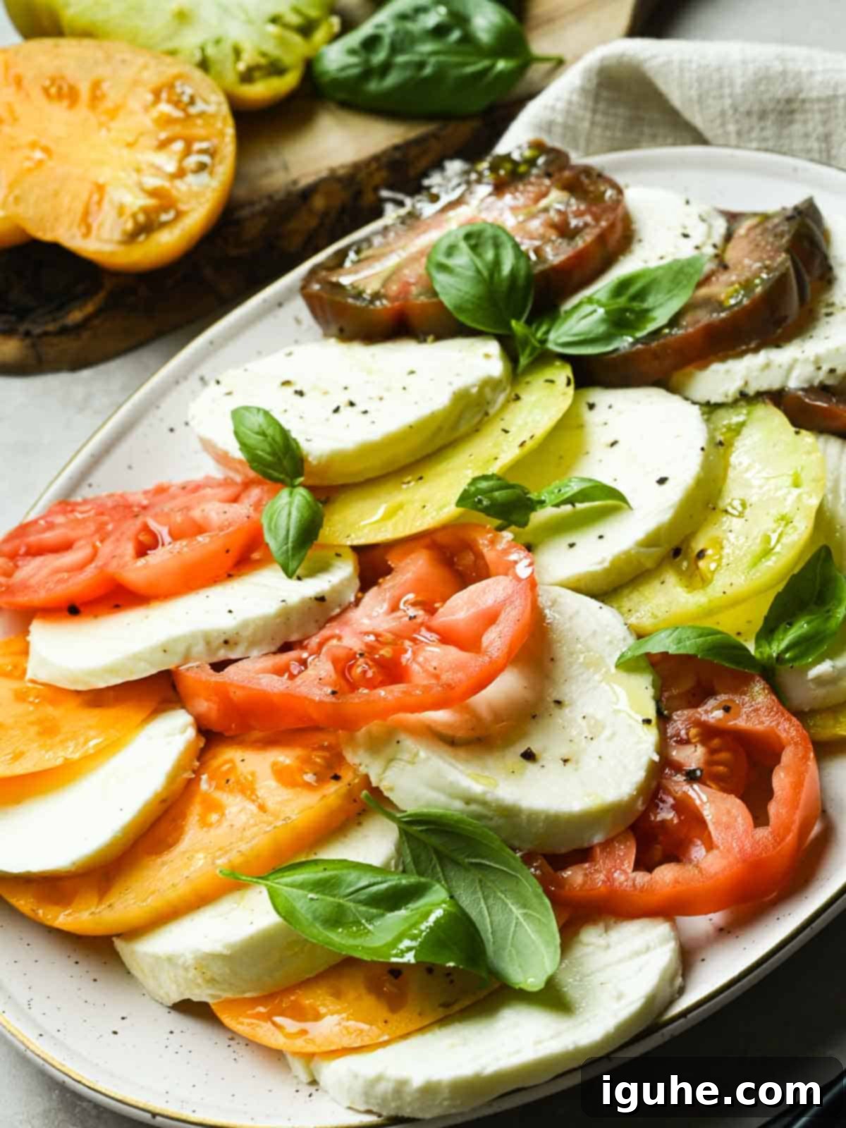 Vibrant Heirloom Caprese Salad 9 Platter of Caprese salad on a beige plate.