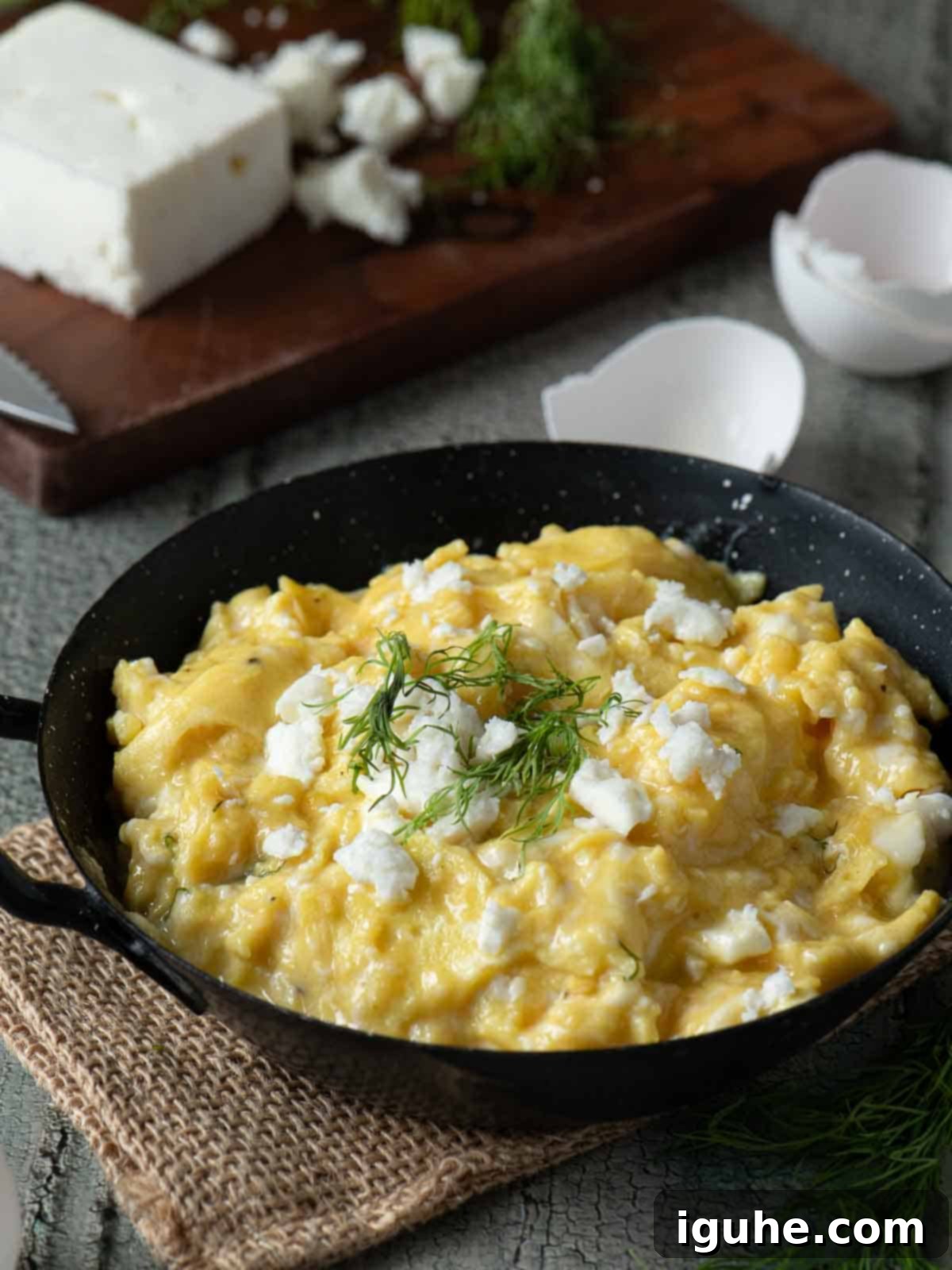 Mediterranean Feta Dill Scramble 2 Angled view of scrambled eggs in a skillet with feta on top.